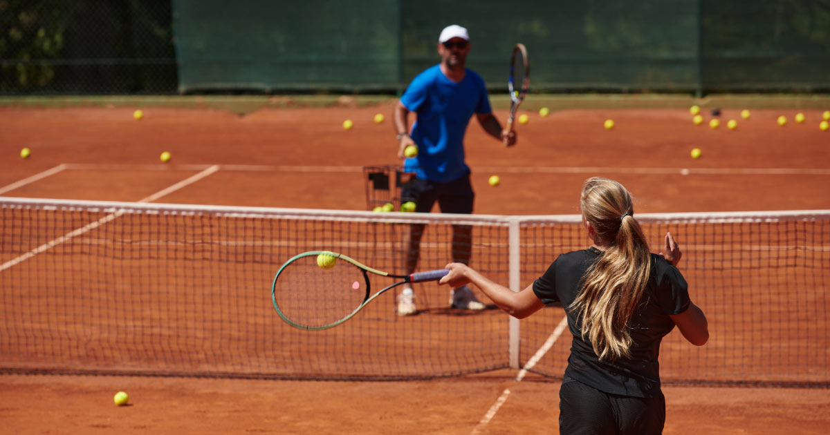 Coach Practicing Shots with Student on Clay Court