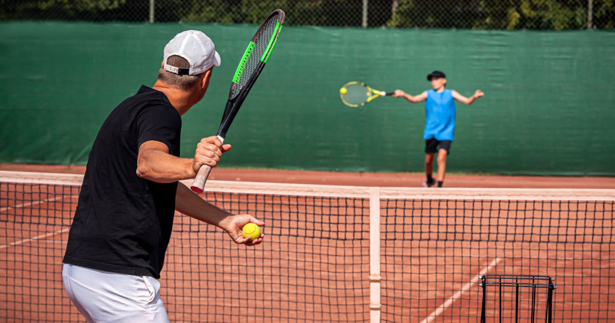 Coach working with young girl to improve her tennis groundstroke shots