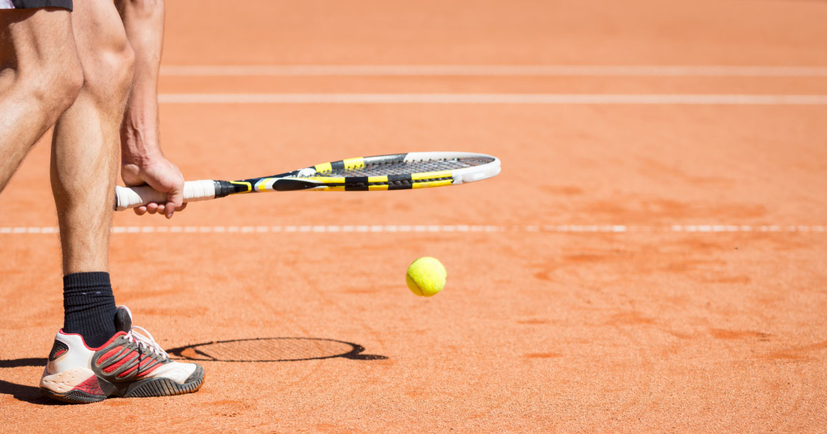 Up close shot of male tennis player bouncing the ball with his racket