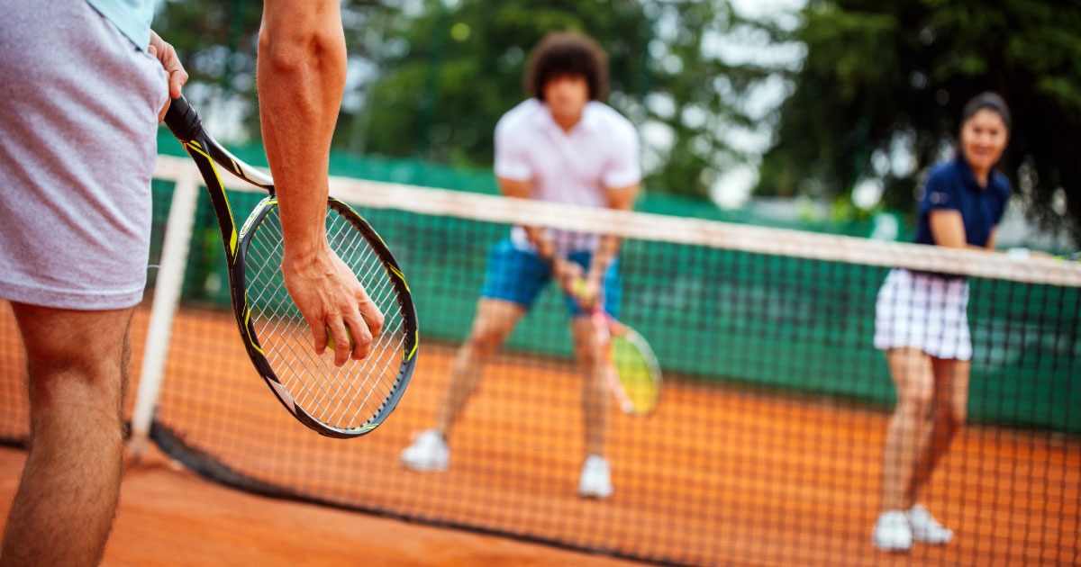 Group of young tennis players having a doubles match on clay court