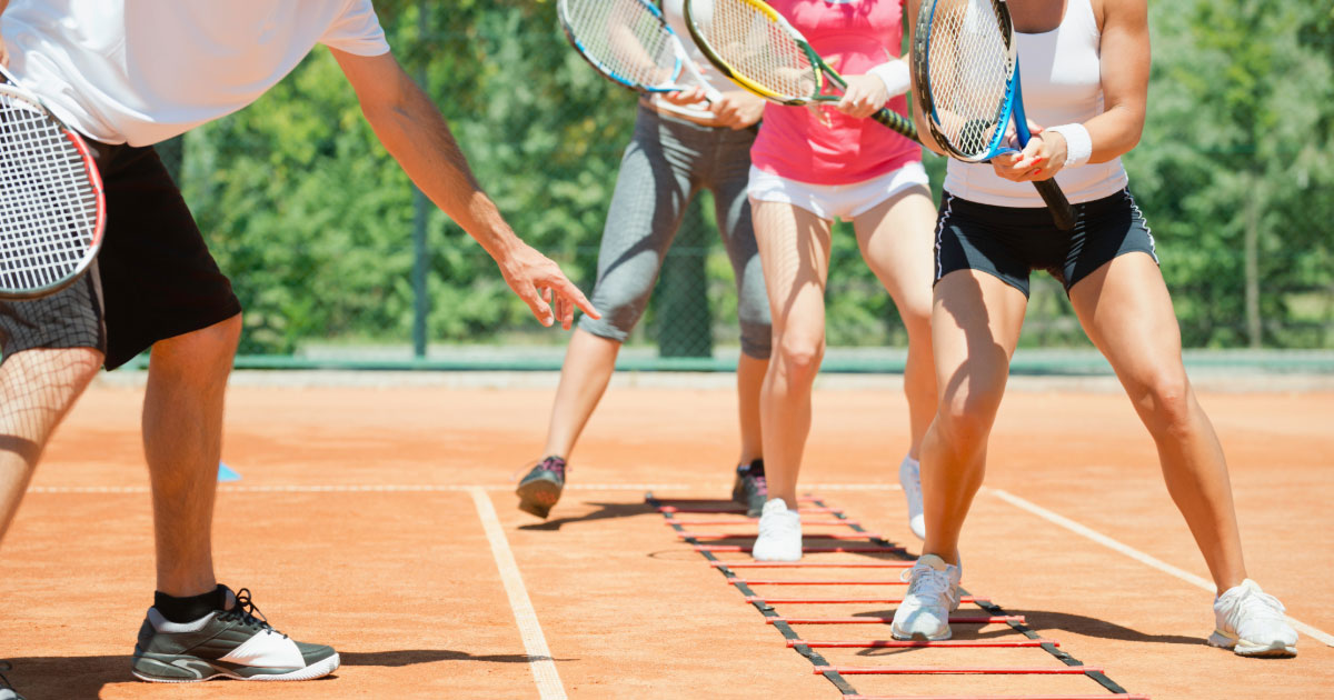 Group tennis class working on footwork with coach